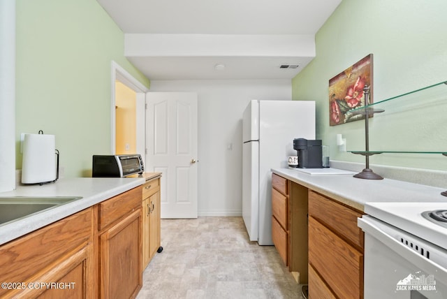10100 Zermatt Cir, Anchorage, AK 99507 - kitchen featuring light countertops, brown cabinetry, and freestanding refrigerator
