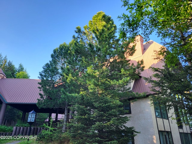 9921 Nearpoint Dr, Anchorage, AK 99507 - view of side of home with stucco siding, a metal roof, and a chimney