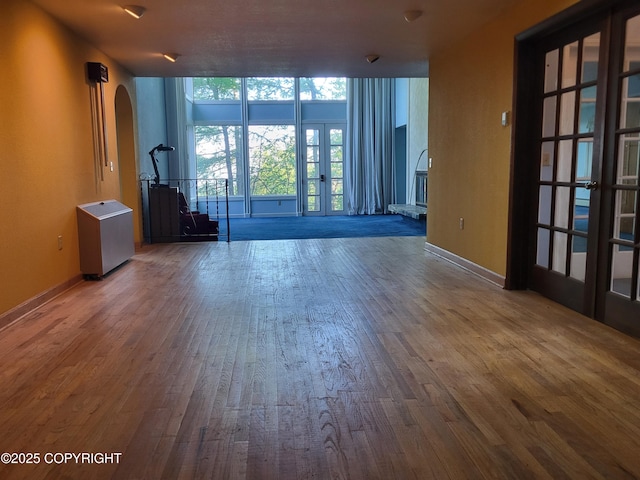 9921 Nearpoint Dr, Anchorage, AK 99507 - empty room with french doors, arched walkways, wood-type flooring, and floor to ceiling windows