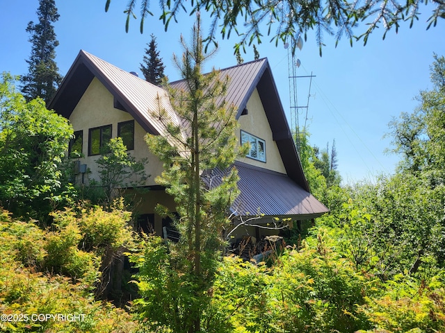 9921 Nearpoint Dr, Anchorage, AK 99507 - view of side of property with stucco siding, a standing seam roof, and a metal roof