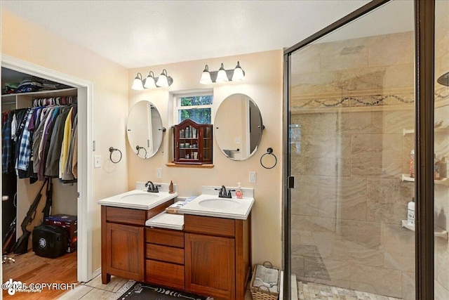 1708 Wesbet Ct, Kenai, AK 99611 - bathroom with a stall shower, two vanities, a walk in closet, and wood finished floors