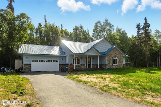 1708 Wesbet Ct, Kenai, AK 99611 - view of front of property featuring stone siding, an attached garage, covered porch, driveway, and a metal roof