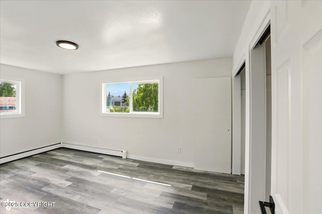 309 Stewart St, Anchorage, AK 99508 - unfurnished bedroom featuring multiple windows, a baseboard radiator, wood finished floors, and a closet