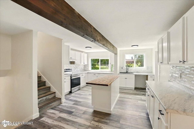 309 Stewart St, Anchorage, AK 99508 - kitchen with stainless steel range with electric cooktop, tasteful backsplash, light wood-style flooring, wood counters, and white cabinetry