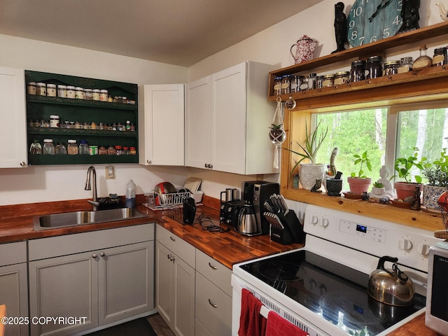 1245 N Miller Cir, Houston, AK 99623 - kitchen with white electric stove, wood counters, open shelves, and white cabinetry