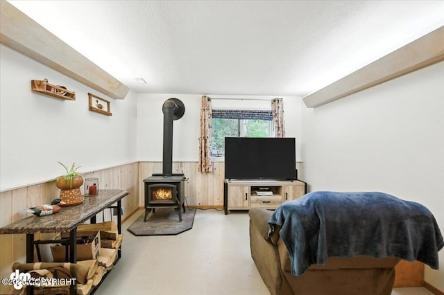 3800 E Birch View Dr, Wasilla, AK 99654 - living area with a wood stove, a wainscoted wall, wood walls, a textured ceiling, and finished concrete floors