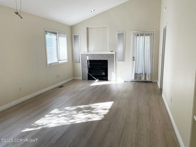 4310 Ambler Cir, Anchorage, AK 99504 - unfurnished living room with a tiled fireplace, lofted ceiling, and wood finished floors