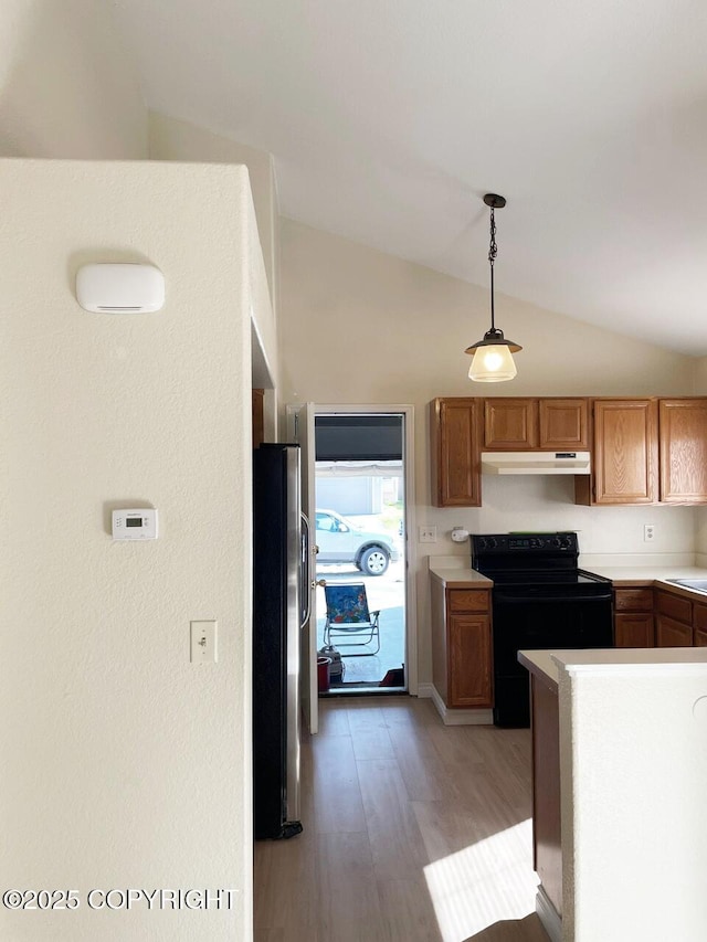 4310 Ambler Cir, Anchorage, AK 99504 - kitchen featuring black range with electric stovetop, under cabinet range hood, vaulted ceiling, stainless steel refrigerator with ice dispenser, and light wood-type flooring
