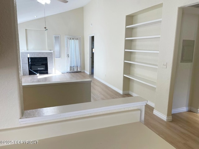 4310 Ambler Cir, Anchorage, AK 99504 - unfurnished living room featuring wood finished floors, electric panel, a fireplace, lofted ceiling, and built in shelves