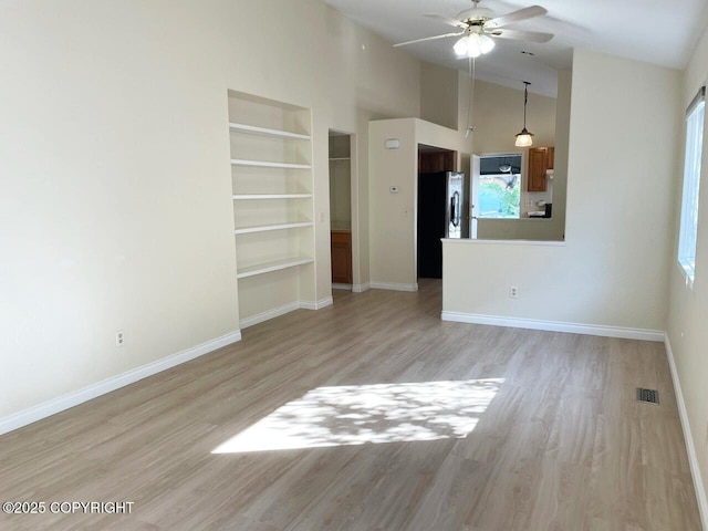 4310 Ambler Cir, Anchorage, AK 99504 - unfurnished living room with light wood-style flooring, a ceiling fan, built in features, and a towering ceiling