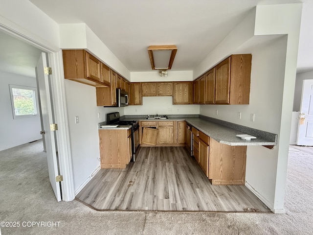 1140 Lalande Pl, Anchorage, AK 99504 - kitchen with black gas range, stainless steel microwave, and brown cabinets