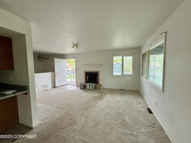 1140 Lalande Pl, Anchorage, AK 99504 - unfurnished living room with carpet flooring, plenty of natural light, a glass covered fireplace, and a ceiling fan