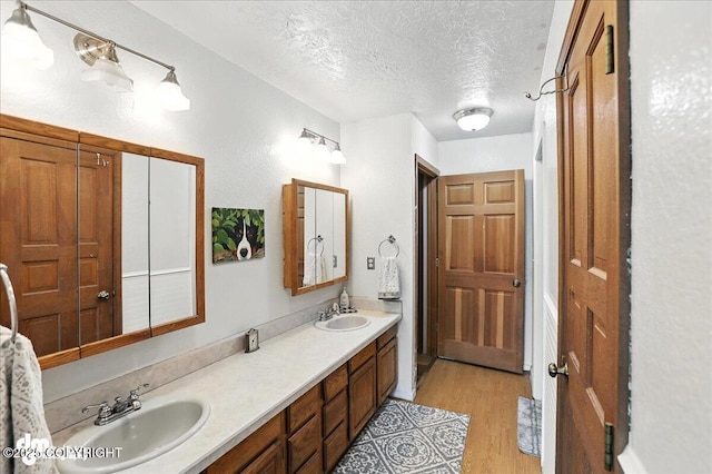 19360 Chugach Park Dr, Chugiak, AK 99567 - bathroom with a textured ceiling, double vanity, and wood finished floors