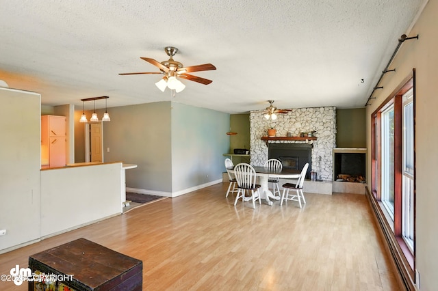 3401 Lois Dr, Anchorage, AK 99517 - dining space featuring ceiling fan, wood finished floors, a stone fireplace, and a textured ceiling