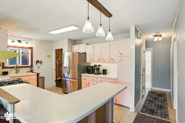 3401 Lois Dr, Anchorage, AK 99517 - kitchen with stainless steel fridge, a textured ceiling, light countertops, decorative light fixtures, and light tile patterned flooring