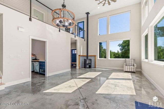 4722 S Gon Fishin Dr, Wasilla, AK 99623 - unfurnished living room with concrete flooring, a chandelier, a wood stove, healthy amount of natural light, and a high ceiling
