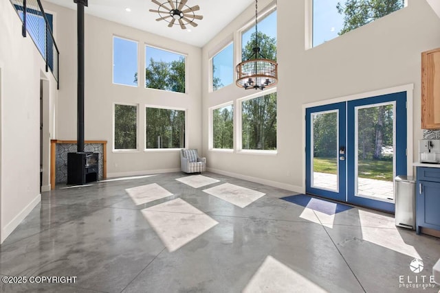4722 S Gon Fishin Dr, Wasilla, AK 99623 - unfurnished living room with concrete floors, a wood stove, french doors, a chandelier, and a towering ceiling