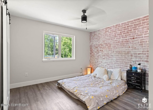 4722 S Gon Fishin Dr, Wasilla, AK 99623 - bedroom with a barn door, wood finished floors, brick wall, and a ceiling fan