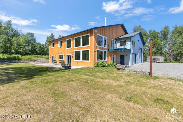 4722 S Gon Fishin Dr, Wasilla, AK 99623 - back of house with an attached garage, a patio area, a balcony, a lawn, and gravel driveway