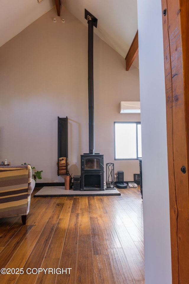 413 N Higgins Ct, Ketchikan, AK 99901 - detailed view of a wood stove, beamed ceiling, wood finished floors, and a wall mounted air conditioner