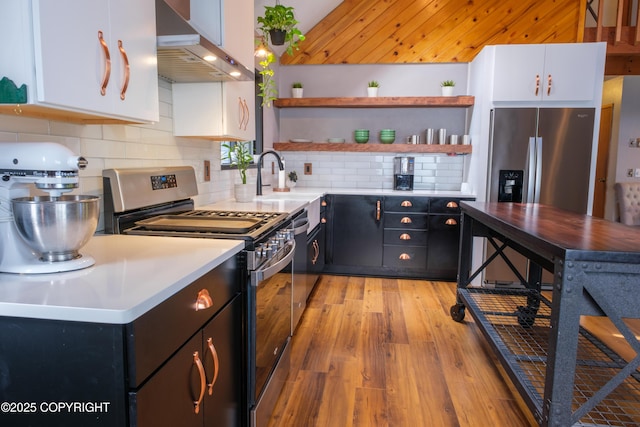 413 N Higgins Ct, Ketchikan, AK 99901 - kitchen with appliances with stainless steel finishes, wall chimney range hood, open shelves, white cabinets, and light wood finished floors