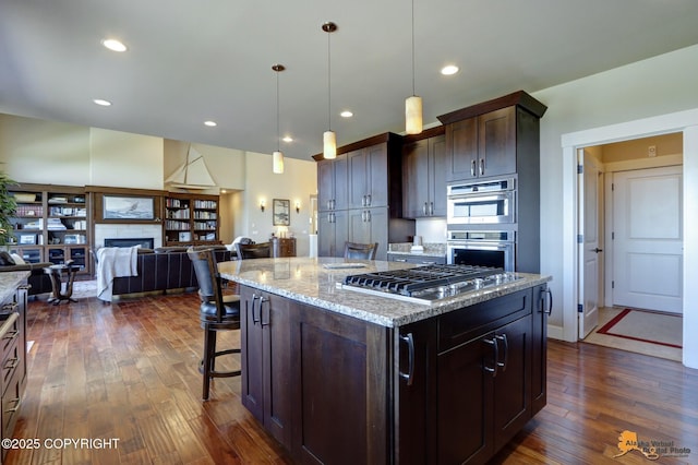16071 Mountain Air Dr, Anchorage, AK 99516 - kitchen featuring stainless steel appliances, dark wood-style floors, a tiled fireplace, light stone counters, and a breakfast bar