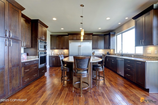 16071 Mountain Air Dr, Anchorage, AK 99516 - kitchen featuring stainless steel appliances, a kitchen island, a breakfast bar, dark wood-style floors, and light stone counters