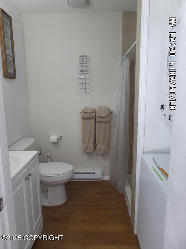 46210 Bonita Ave, Soldotna, AK 99669 - full bath featuring a baseboard radiator, washer / clothes dryer, vanity, wood finished floors, and shower / bath combo with shower curtain