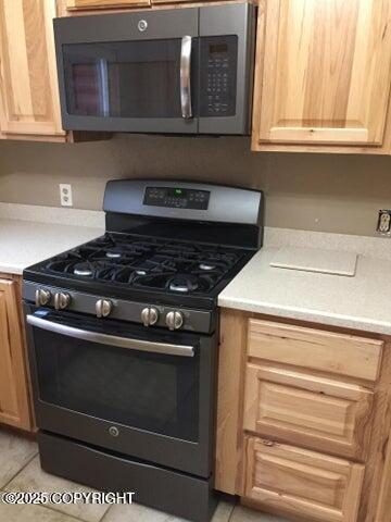 53245 Coyote Ln, Nikiski/North Kenai, AK 99611 - kitchen with range with gas cooktop, stainless steel microwave, light countertops, and light tile patterned floors