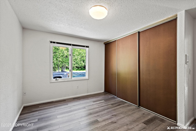 19712 Chugach Park Dr, Eagle River, AK 99567 - unfurnished bedroom with a textured ceiling, wood finished floors, a closet, and a textured wall