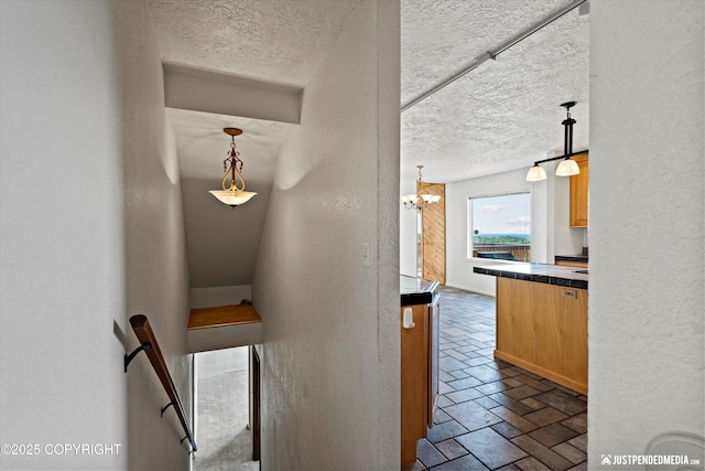 19712 Chugach Park Dr, Eagle River, AK 99567 - stairway featuring a textured ceiling, a chandelier, a textured wall, and stone tile floors