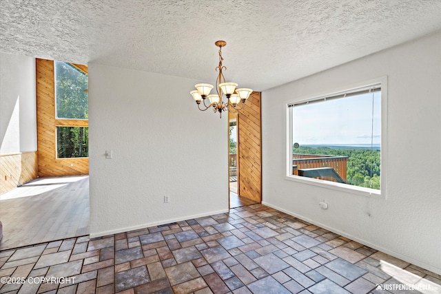 19712 Chugach Park Dr, Eagle River, AK 99567 - spare room with wooden walls, a chandelier, plenty of natural light, and a textured ceiling