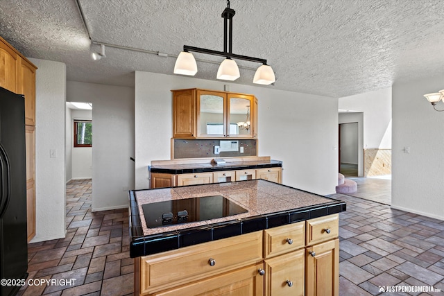 19712 Chugach Park Dr, Eagle River, AK 99567 - kitchen featuring black appliances, glass insert cabinets, tile counters, hanging light fixtures, and tasteful backsplash