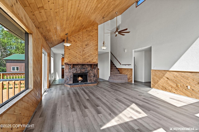 19712 Chugach Park Dr, Eagle River, AK 99567 - unfurnished living room with wood walls, stairs, ceiling fan, wood finished floors, and a fireplace