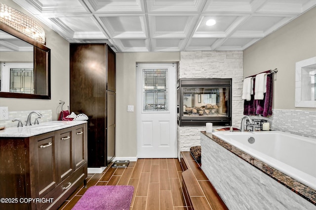 3890 Janet Lee Cir, Anchorage, AK 99516 - bathroom featuring coffered ceiling, vanity, a stone fireplace, a garden tub, and wood finished floors