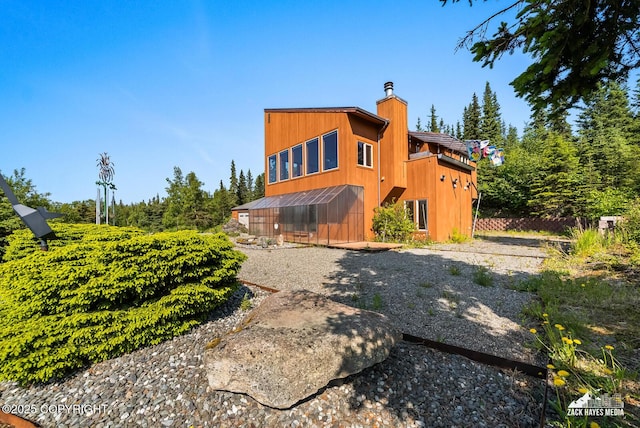 11411 Snowline Dr, Anchorage, AK 99507 - rear view of house with a chimney, an exterior structure, and an outbuilding