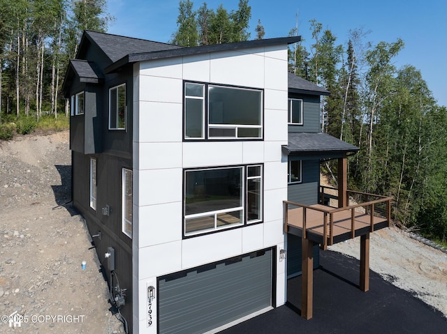 17939 Yellowstone Dr, Eagle River, AK 99577 - modern home featuring an attached garage, a shingled roof, and a deck