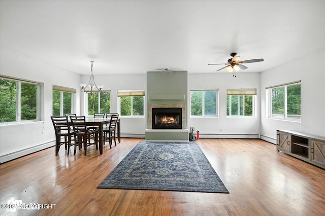 1447 N Ranch Rd, Palmer, AK 99645 - dining space featuring a warm lit fireplace, wood finished floors, a ceiling fan, a baseboard heating unit, and a baseboard radiator