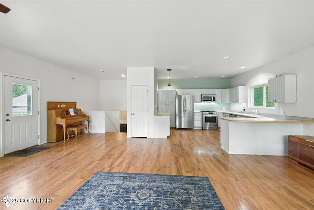 1447 N Ranch Rd, Palmer, AK 99645 - kitchen featuring appliances with stainless steel finishes, light wood-style flooring, a peninsula, light countertops, and white cabinetry