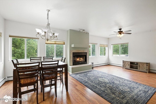 1447 N Ranch Rd, Palmer, AK 99645 - dining space featuring a tiled fireplace, wood finished floors, ceiling fan, a chandelier, and a baseboard radiator