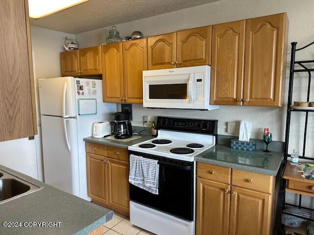 100 Kenai St # 908, Whittier, AK 99693 - kitchen with white appliances, brown cabinets, and light tile patterned flooring
