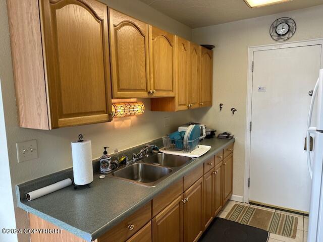 100 Kenai St # 908, Whittier, AK 99693 - kitchen with freestanding refrigerator, dark countertops, and tile patterned flooring