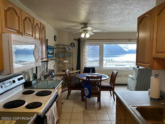 100 Kenai St # 908, Whittier, AK 99693 - kitchen featuring electric range, white microwave, ceiling fan, light tile patterned floors, and a textured ceiling