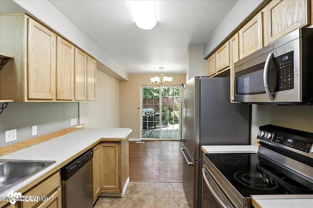 6403 E 10th Ave # 26, Anchorage, AK 99504 - kitchen with stainless steel appliances, light brown cabinetry, light countertops, a chandelier, and a peninsula