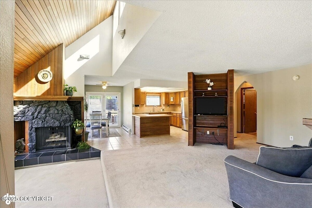 6340 Habicht Ct, Anchorage, AK 99504 - living area featuring light carpet, ceiling fan, vaulted ceiling, a tiled fireplace, and arched walkways