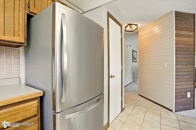 6340 Habicht Ct, Anchorage, AK 99504 - kitchen featuring freestanding refrigerator, a textured ceiling, light countertops, light tile patterned floors, and tasteful backsplash