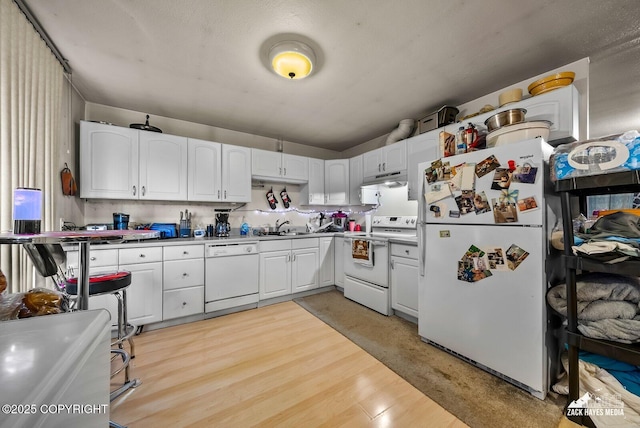 4116 W 88th Ave, Anchorage, AK 99502 - kitchen with white appliances, white cabinetry, under cabinet range hood, and light wood-style floors