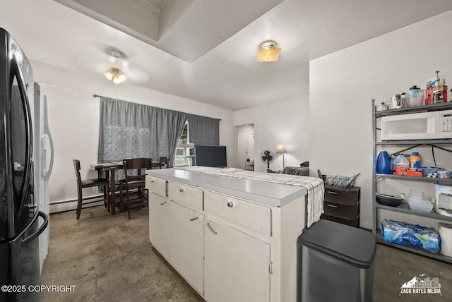 4116 W 88th Ave, Anchorage, AK 99502 - kitchen with white microwave, a baseboard radiator, white cabinets, freestanding refrigerator, and concrete floors