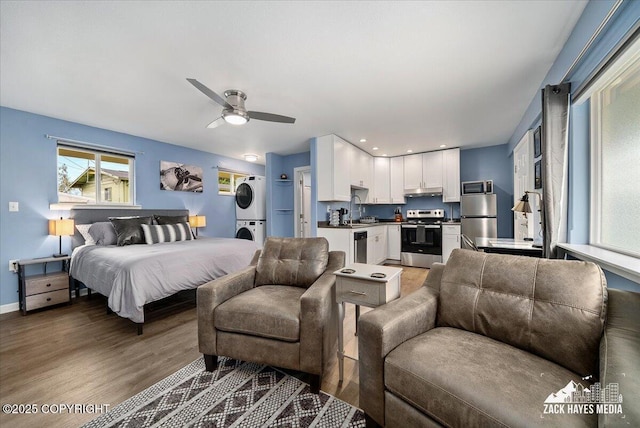 4116 W 88th Ave, Anchorage, AK 99502 - bedroom with stacked washing machine and dryer, freestanding refrigerator, and wood finished floors