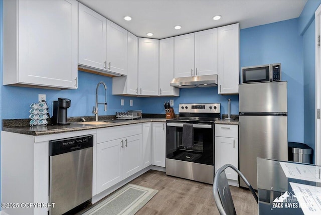 4116 W 88th Ave, Anchorage, AK 99502 - kitchen featuring stainless steel appliances, under cabinet range hood, recessed lighting, white cabinetry, and light wood-style flooring